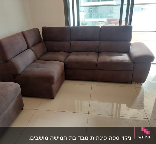 ספה חומה על רצפה מבריקה ליד חלון גדול